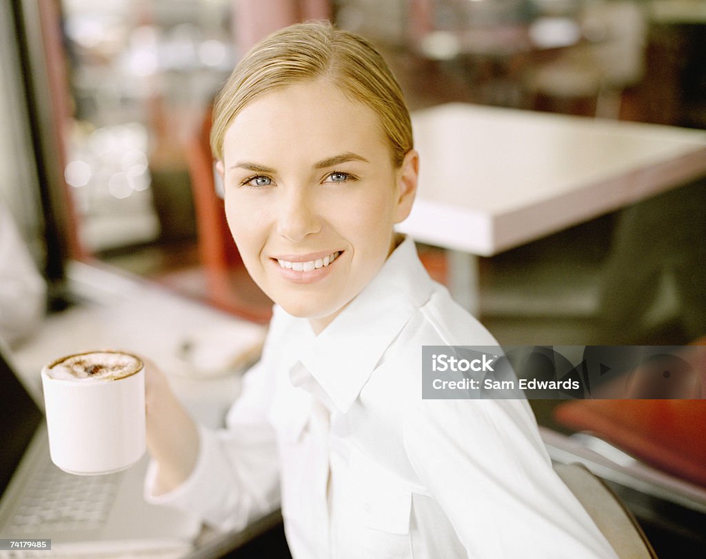 Femme d'affaires avec ordinateur portable ayant un café et un assistant numérique personnel - Photo de 20-24 ans libre de droits