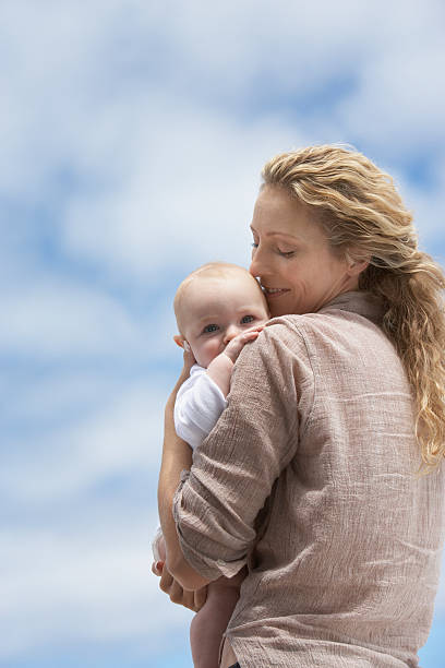 женщина держит ребенок на открытом воздухе - babies and children cheerful low angle view vertical стоковые фото и изображения