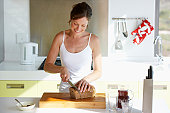 Woman in kitchen slicing bread
