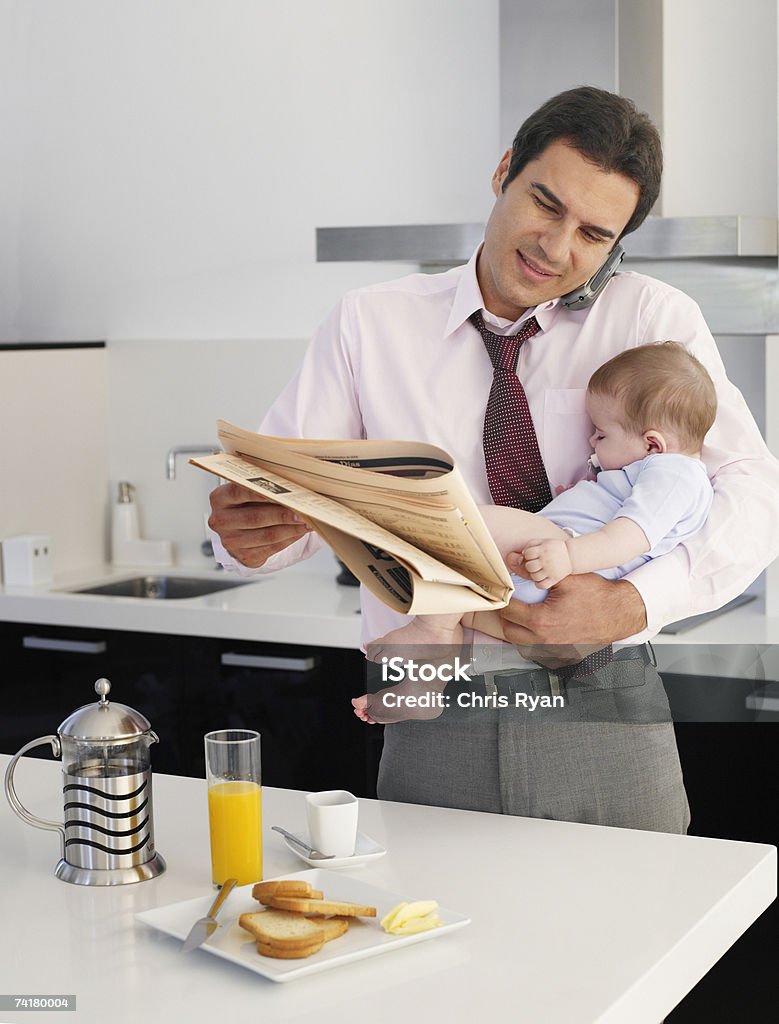 Geschäftsmann holding Schlafen baby und Zeitung sprechen auf Zelle - Lizenzfrei Familie Stock-Foto