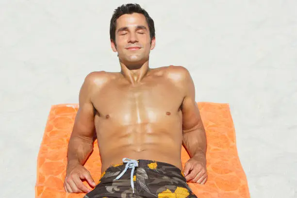 Photo of Man lying down on beach towel in sand