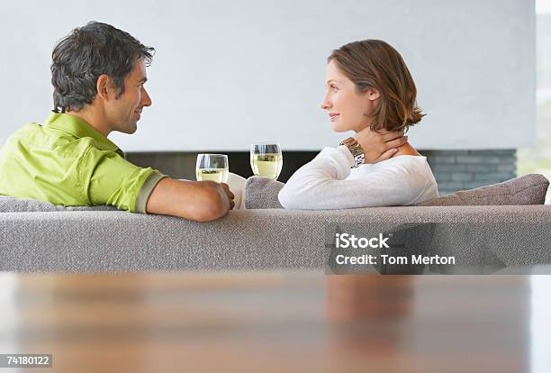 Uomo E Donna Seduta Sul Divano Con Bicchieri Di Vino - Fotografie stock e altre immagini di 25-29 anni