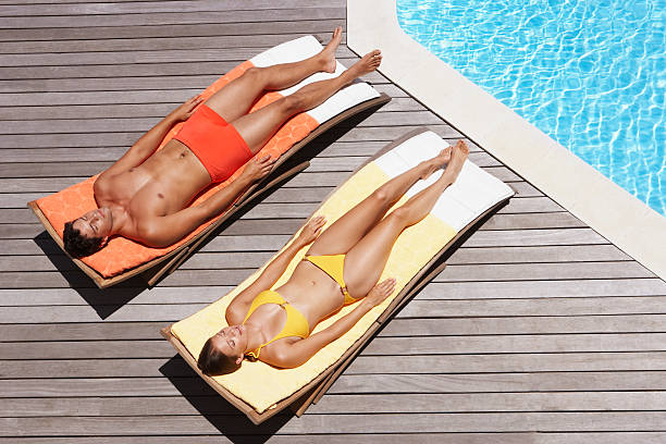 男性と女性のプールデッキでの日光浴 - deck chair ストックフォトと画像
