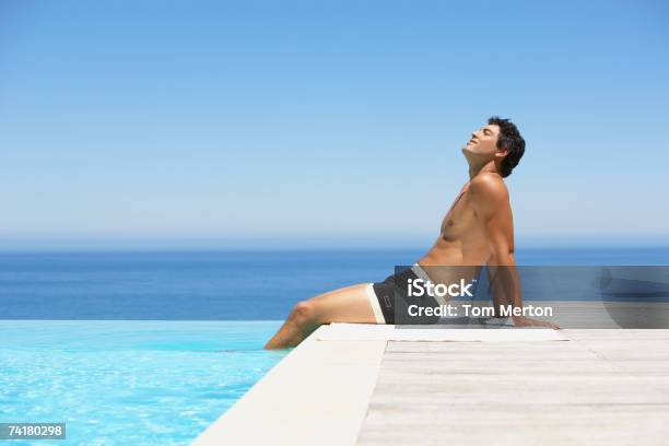 Man On Infinity Pool Deck In Swimsuit Stock Photo - Download Image Now - Sunbathing, Swimming Pool, Full Length