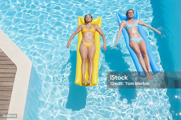 Duas Mulheres Na Piscina Dispositivos De Flutuação Na - Fotografias de stock e mais imagens de Flutuar na Água