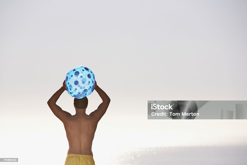 Homem em trajes de banho com bola de praia Vista traseira - Foto de stock de 20-24 Anos royalty-free