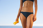 Midsection of woman in bikini with sun block