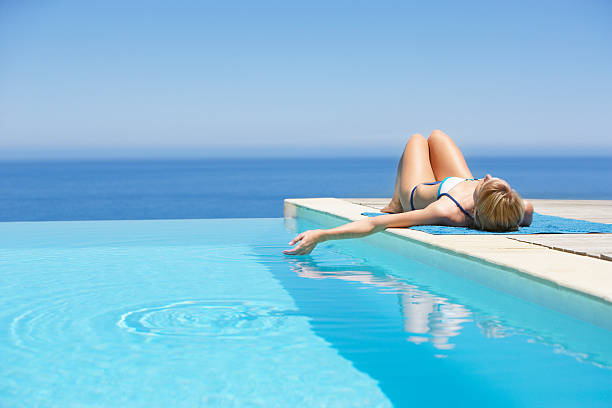 frau sonnenbaden auf der terrasse mit infinity-pool - vacations infinity pool relaxation women stock-fotos und bilder