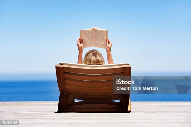 Rear View Of Woman Reading Outdoors In Wooden Chair Stock Photo - Download Image Now