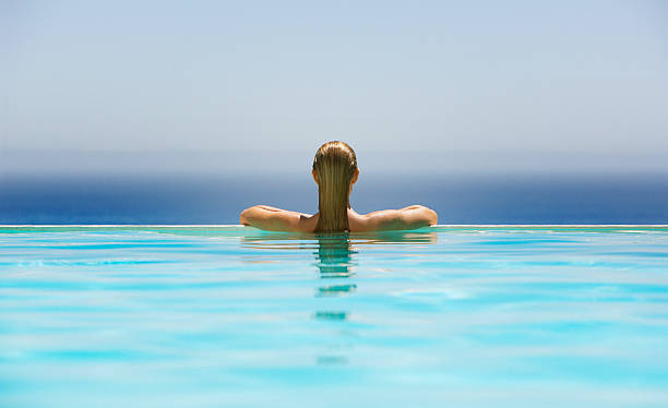 donna nella piscina a sfioro - heat female summer vacations foto e immagini stock