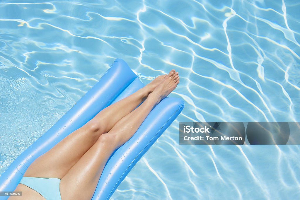 Donna in bikini sul dispositivo di galleggiamento in piscina - Foto stock royalty-free di 20-24 anni