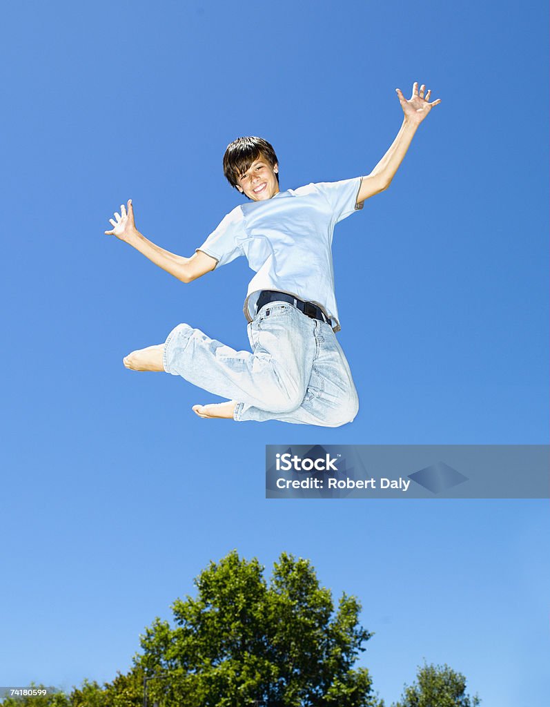 Мальчик leaping на открытом воздухе с Голубое небо и деревья - Стоковые фото 14-15 лет роялти-фри