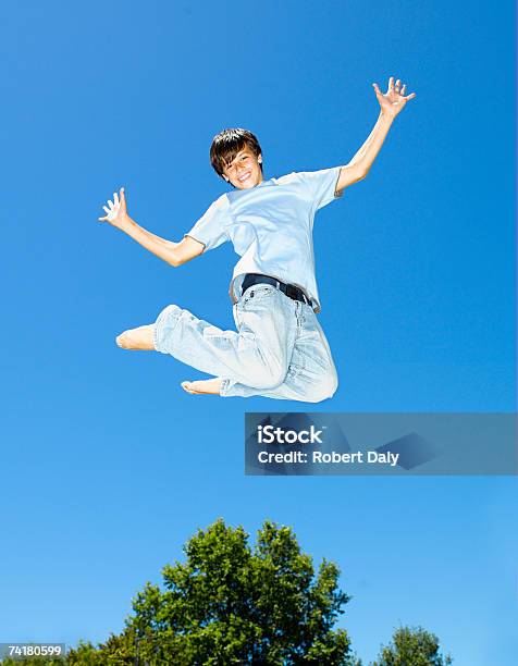 Мальчик Leaping На Открытом Воздухе С Голубое Небо И Деревья — стоковые фотографии и другие картинки 14-15 лет