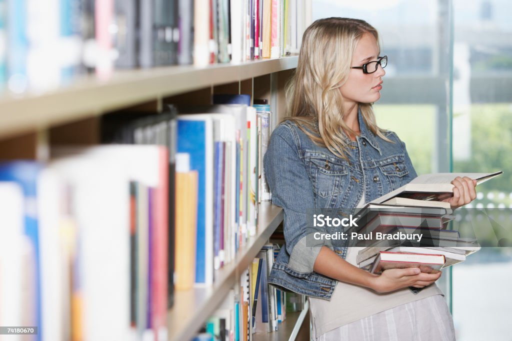 Jovem mulher na biblioteca, com livros escolares - Foto de stock de Livro royalty-free