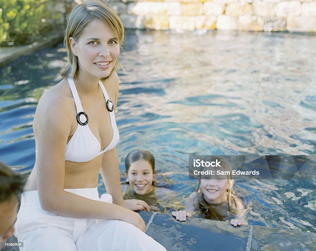 Dos chicas en la piscina al aire libre con madre - Foto de stock de 20-24 años libre de derechos