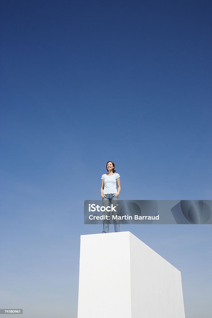 Kobieta stojąc na ścianie na świeżym powietrzu z niebieski niebo - Zbiór zdjęć royalty-free (25-29 lat)