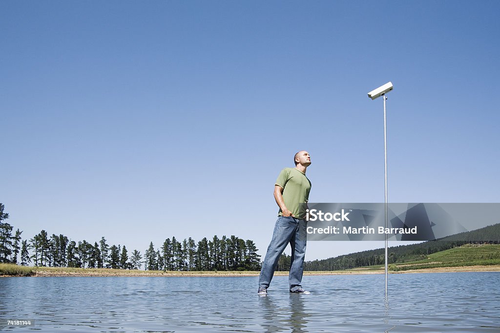 Uomo in piedi in acqua con Telecamera di sorveglianza - Foto stock royalty-free di 20-24 anni