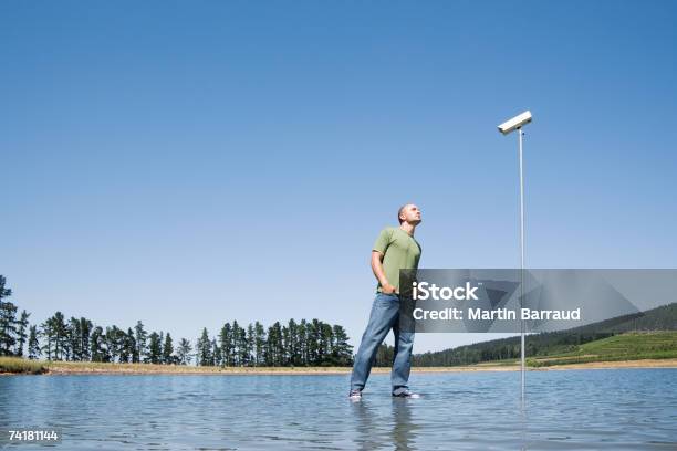 Uomo In Piedi In Acqua Con Telecamera Di Sorveglianza - Fotografie stock e altre immagini di 20-24 anni