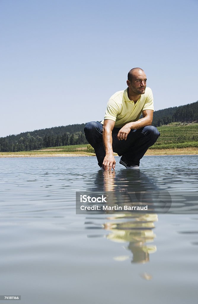 Hombre de crouching en agua - Foto de stock de 20-24 años libre de derechos