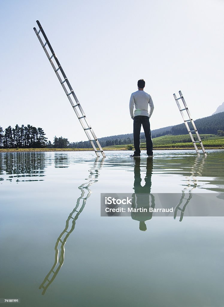 Homme debout sur les échelles de l'eau avec - Photo de 25-29 ans libre de droits