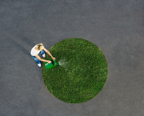 Mujer riego de césped en un círculo de pavimento photo