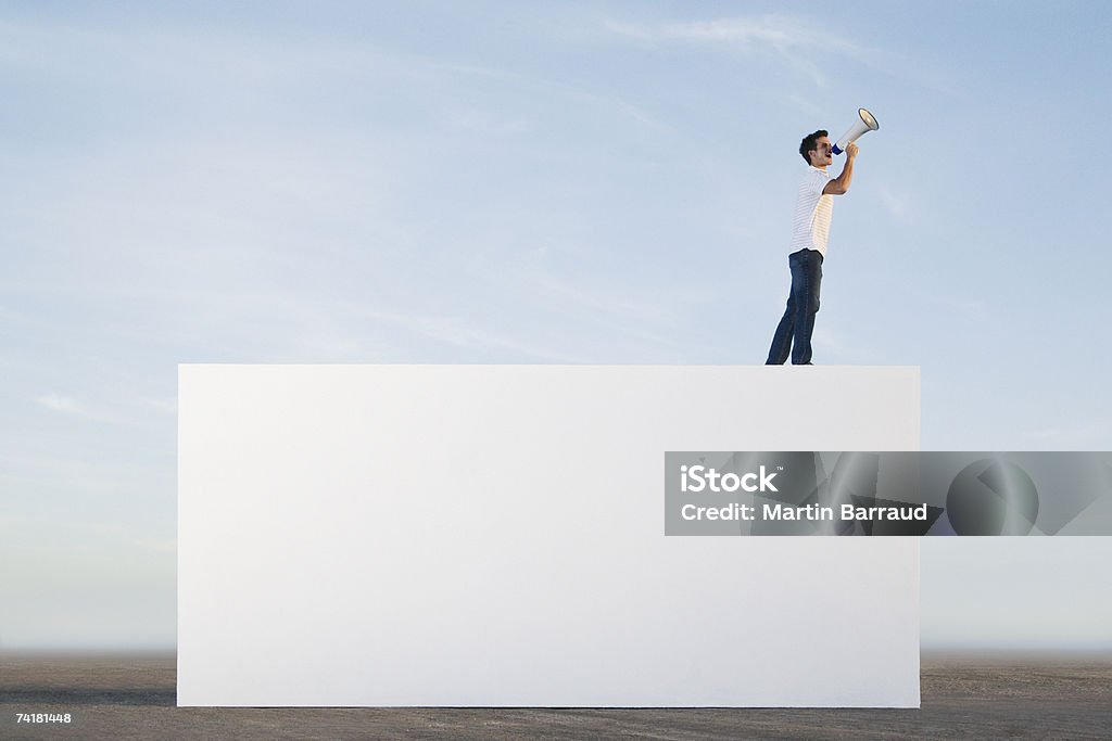 Człowiek stojący na ścianę z Megafon na zewnątrz - Zbiór zdjęć royalty-free (Megafon)