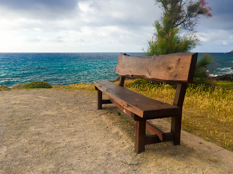 Bench with a view over the Weissensee or Weißensee lake in Carinthia in Austria within the Gailtal Alps mountain range during an overcast springtime day.