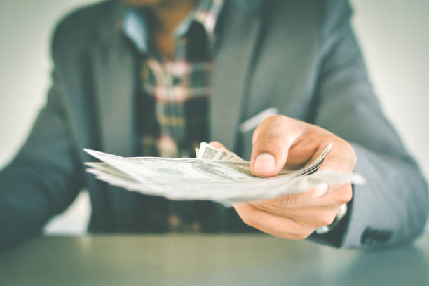 istock Midsection Of Businessman Holding Paper Currency At Table 748586521
