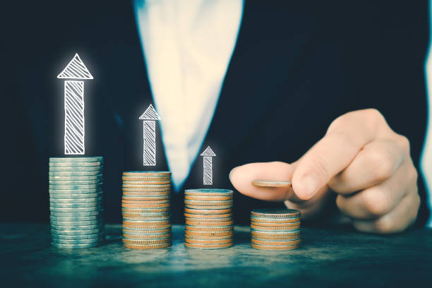 istock Midsection Of Businessman Placing Coins In Stack With Arrow Symbol On Table 750560561