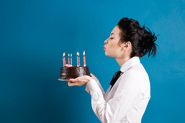 Young woman blowing out birthday candles  woman birthday cake stock pictures, royalty-free photos & images