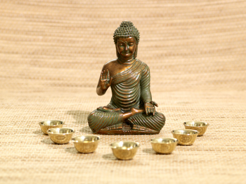 Brown Buddha figurine with a bowl on green background. Perfect for putting through editing your own element coming out of the bowl. Added grain.