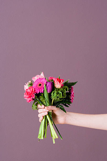 person holding bunch of flowers - hand holding flowers 뉴스 사진 이미지