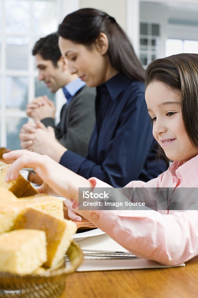 Ragazza prendendo pane mentre i genitori dicono grace - Foto stock royalty-free di Bambino