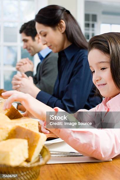 Ragazza Prendendo Pane Mentre I Genitori Dicono Grace - Fotografie stock e altre immagini di Bambino