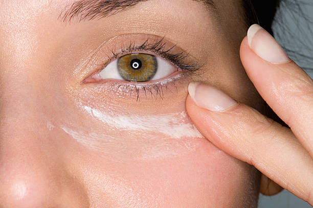 mujer aplicar crema humectante - ojo humano fotografías e imágenes de stock