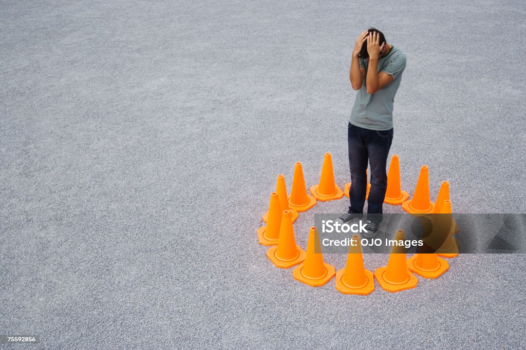 Homem cercado por cones de segurança - Foto de stock de Encurralado royalty-free