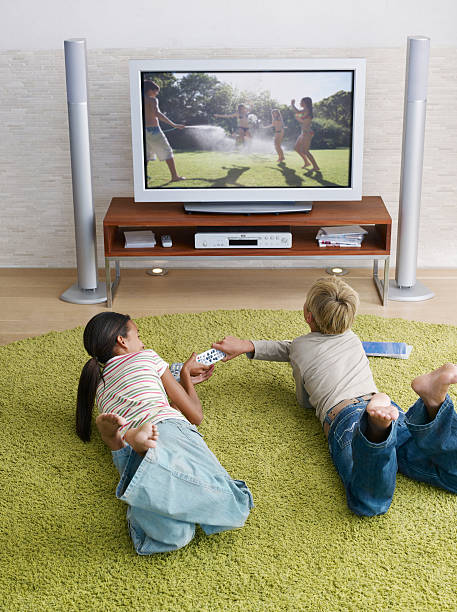 две молодые дети сражение на телевизионных пультов дистанционного - family television fighting watching стоковые фото и изображения