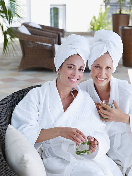 due donne rilassante in accappatoio con drink naturali - tea women beauty pampering foto e immagini stock