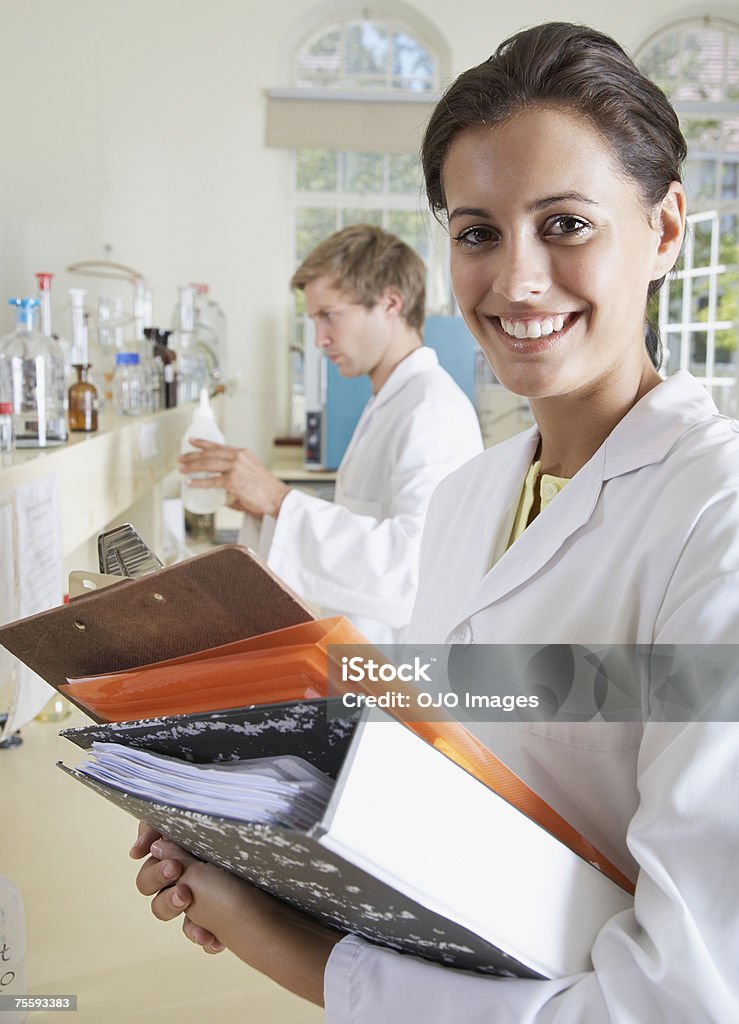 Donna in un laboratorio tenendo un appunti con un - Foto stock royalty-free di Laboratorio