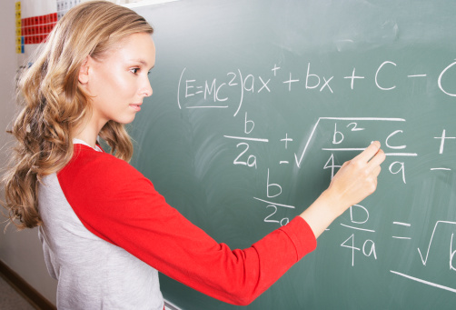 Female teacher standing in front of chalkboard and explaining mathematic during online class.