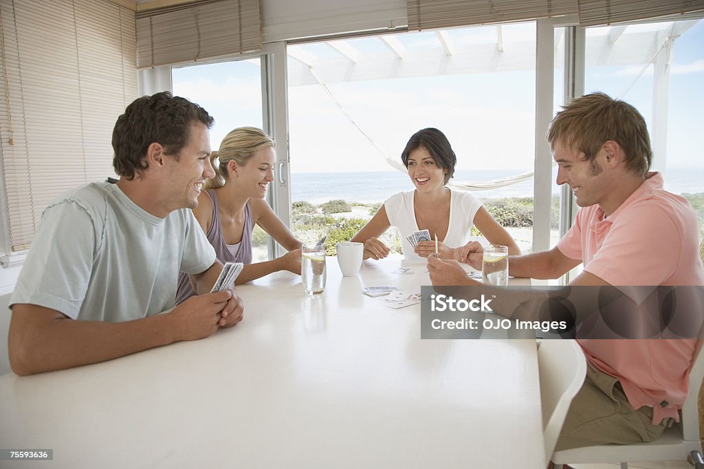 Two couples at a table playing cards  18-19 Years Stock Photo