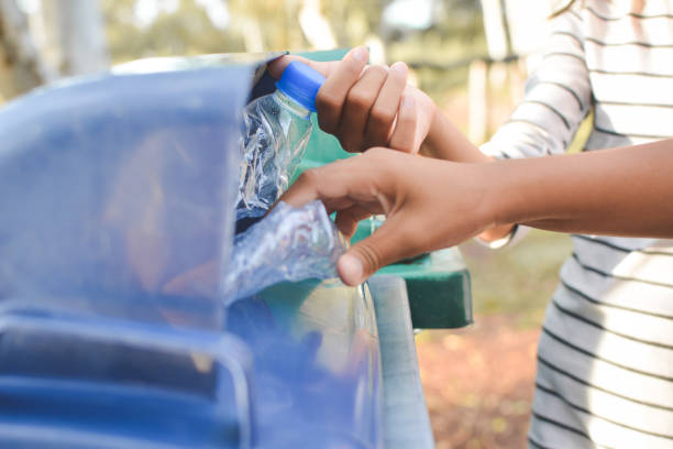 istock Cropped Image Of Hands Throwing Crushed Bottles In Recycling Bin 758480757