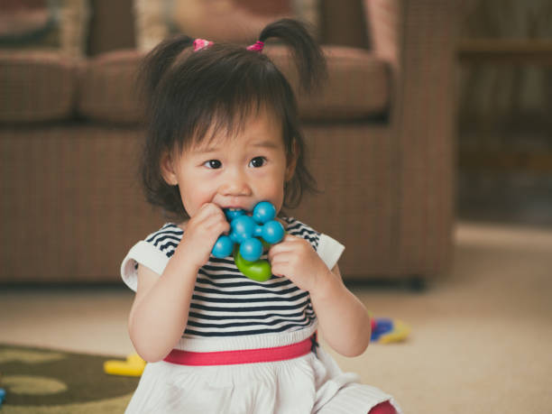 istock Cute Girl Biting Toy While Sitting At Home 758535261