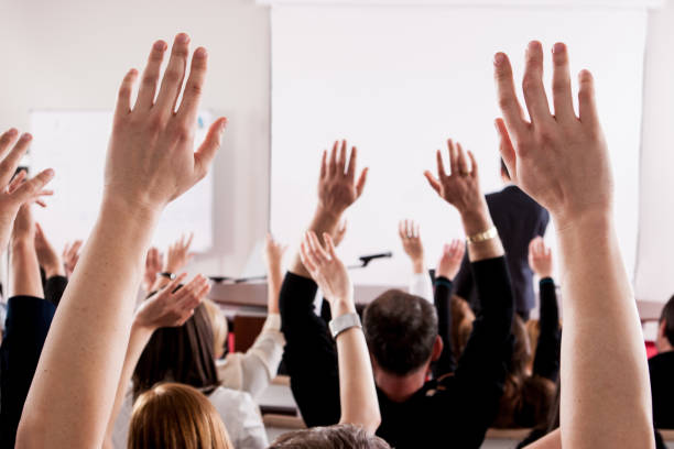 istock People With Arms Raised In Lecture Hall During Seminar 758589745