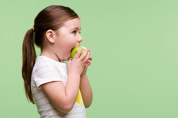 dziewczynka jeść jabłko - apple eating little girls green zdjęcia i obrazy z banku zdjęć