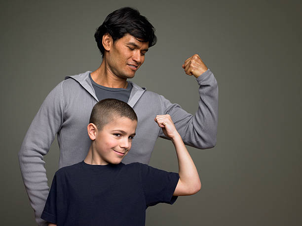 padre e figlio flettere i muscoli - flexing muscles child little boys bicep foto e immagini stock