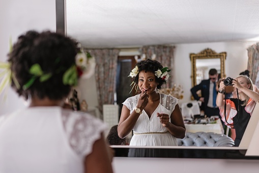Reflejo de la novia aplicando lápiz labial mientras está parada frente al espejo photo