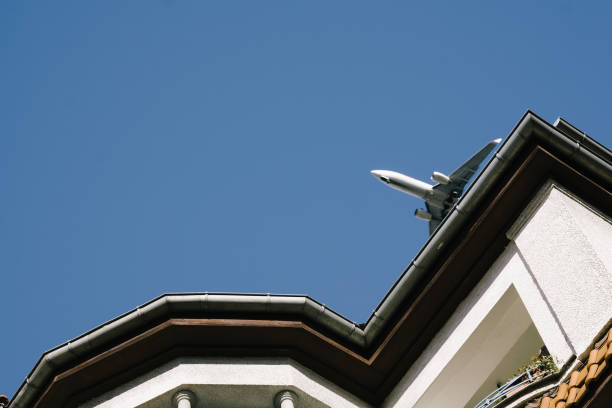 istock Low Angle View Of Airplane Flying Over Building Against Clear Sky 769812375