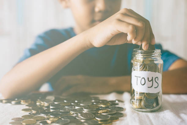 istock Midsection Of Boy Putting Coins In Jar On Table 771535285