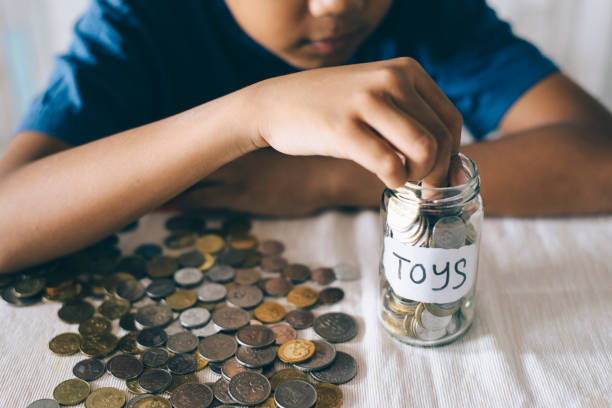istock Midsection Of Boy Putting Coins In Jar On Table 771539307